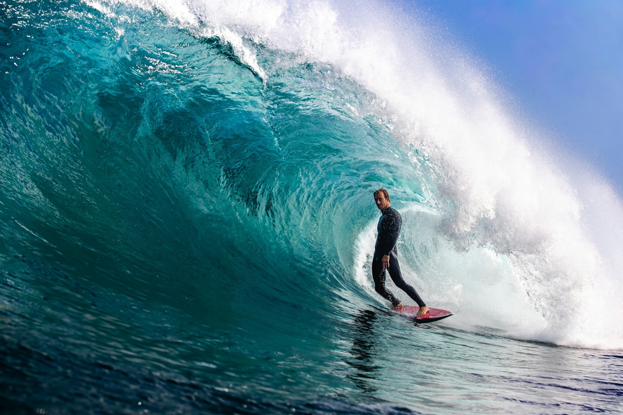 A surfer riding inside a breaking wave