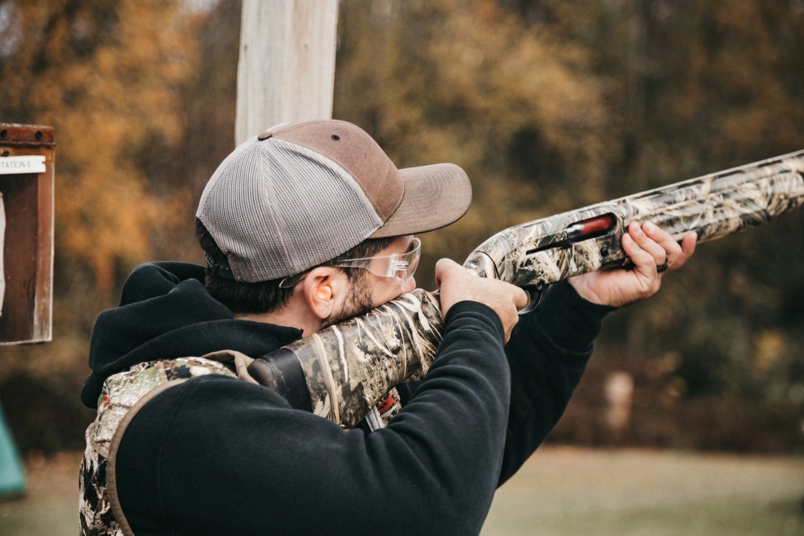 A shooter aiming a shotgun on a clay range